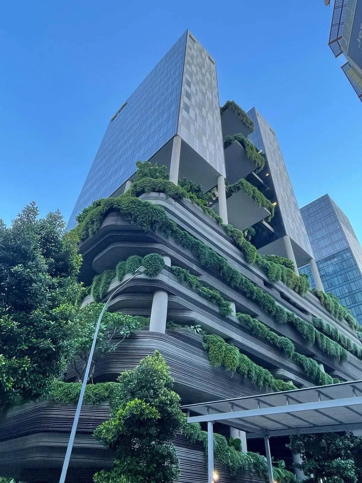 Cascading planted terraces wrapping a tower, biophilia built into the facade, Singapore 2023