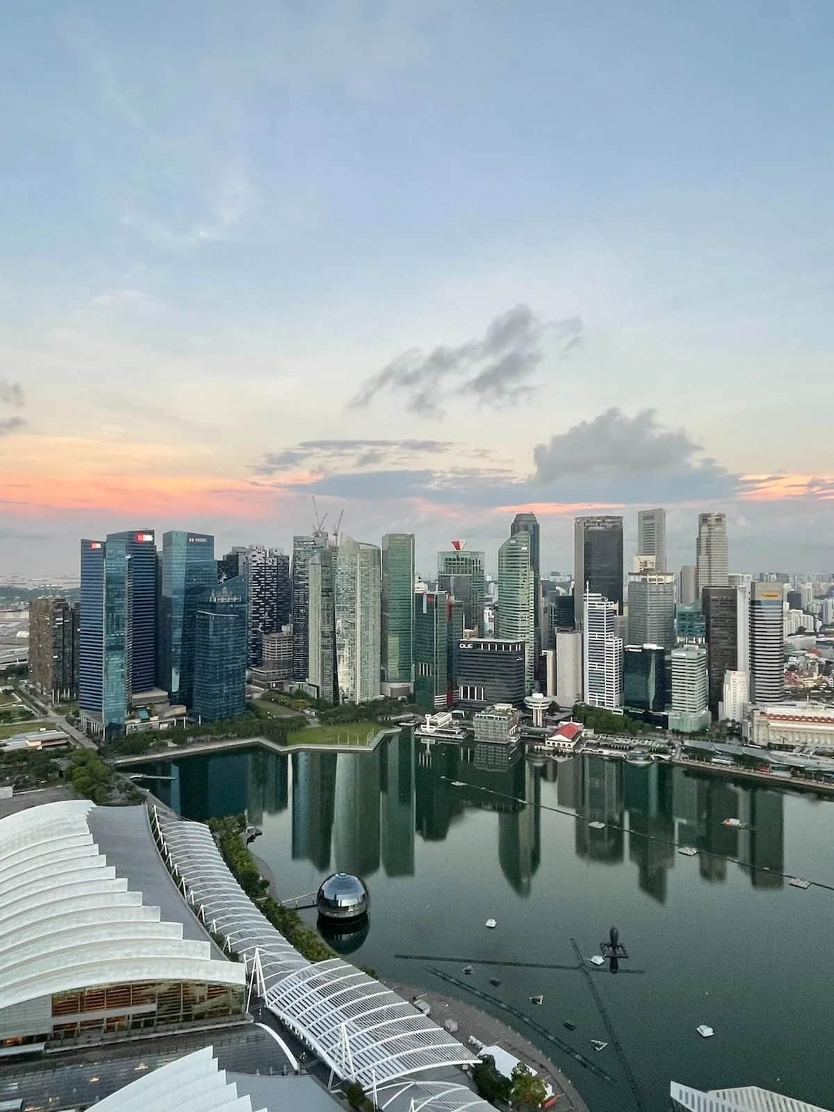 The financial district skyline mirrored in the bay at dusk, seen from a hotel roof, Singapore 2023