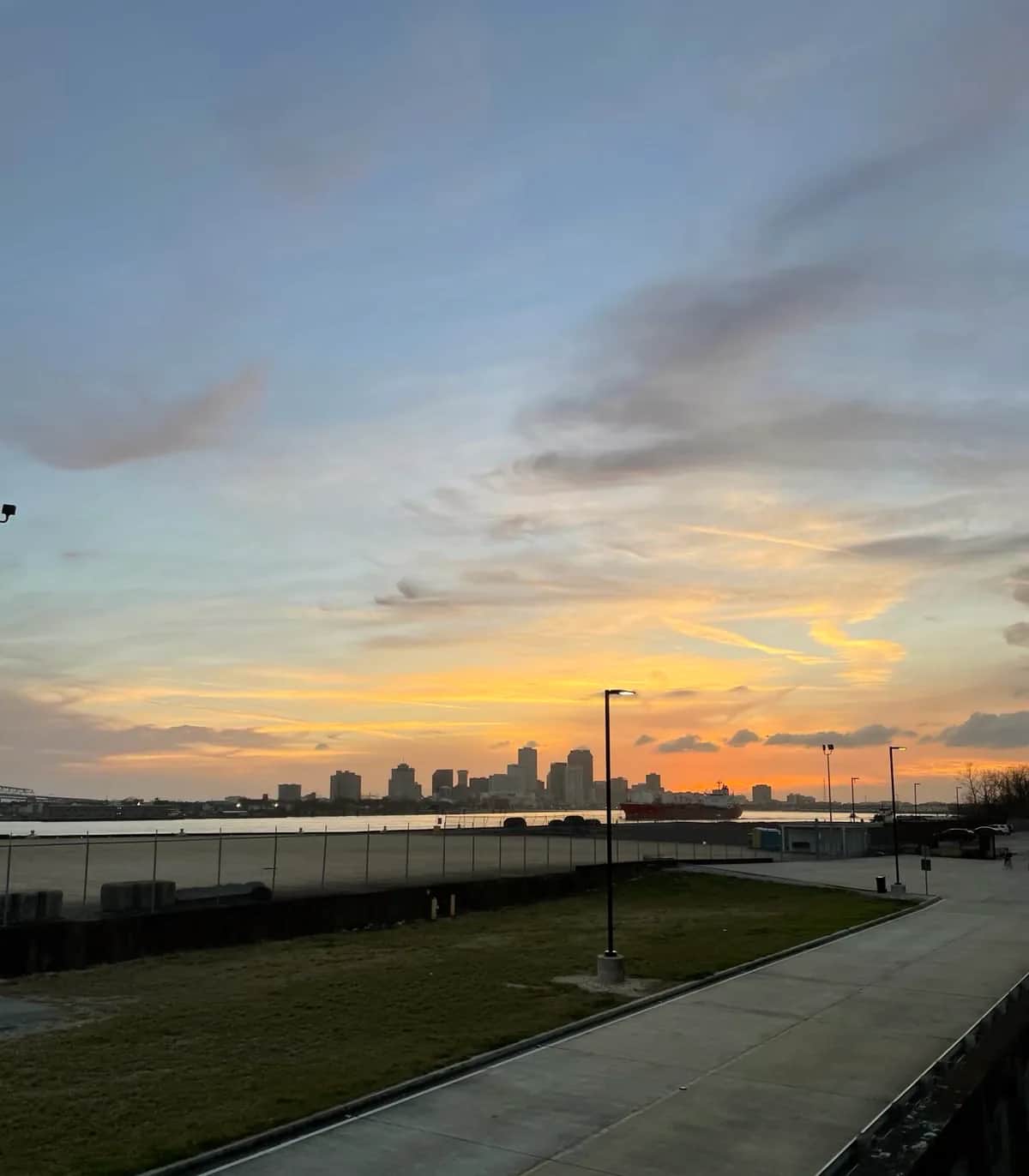 Sunset over the river from the Bywater with a red tanker below the skyline, New Orleans 2021