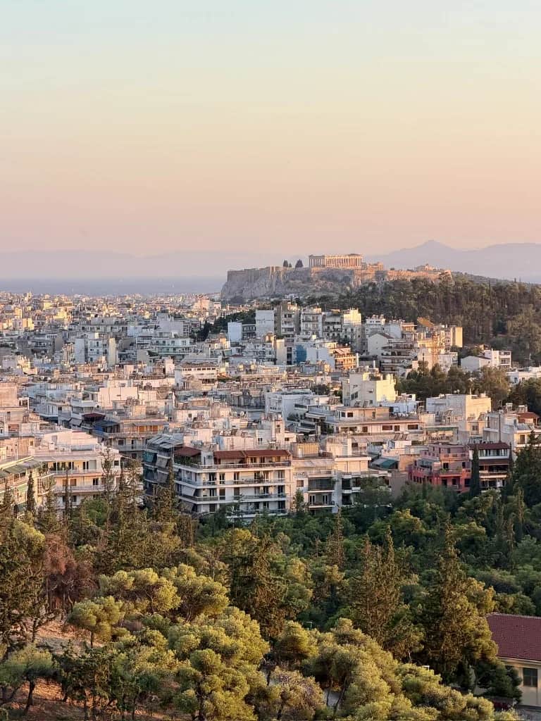 The Acropolis standing above the roofs and pines at sunset, Athens