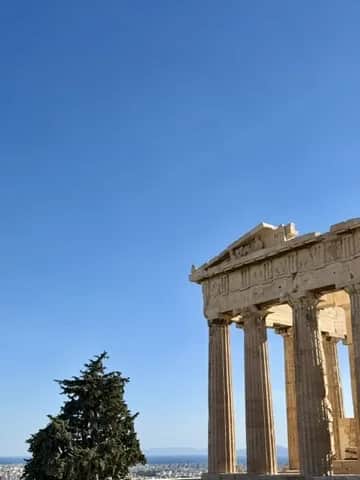 The corner columns and pediment of the Parthenon beside a single pine, Athens