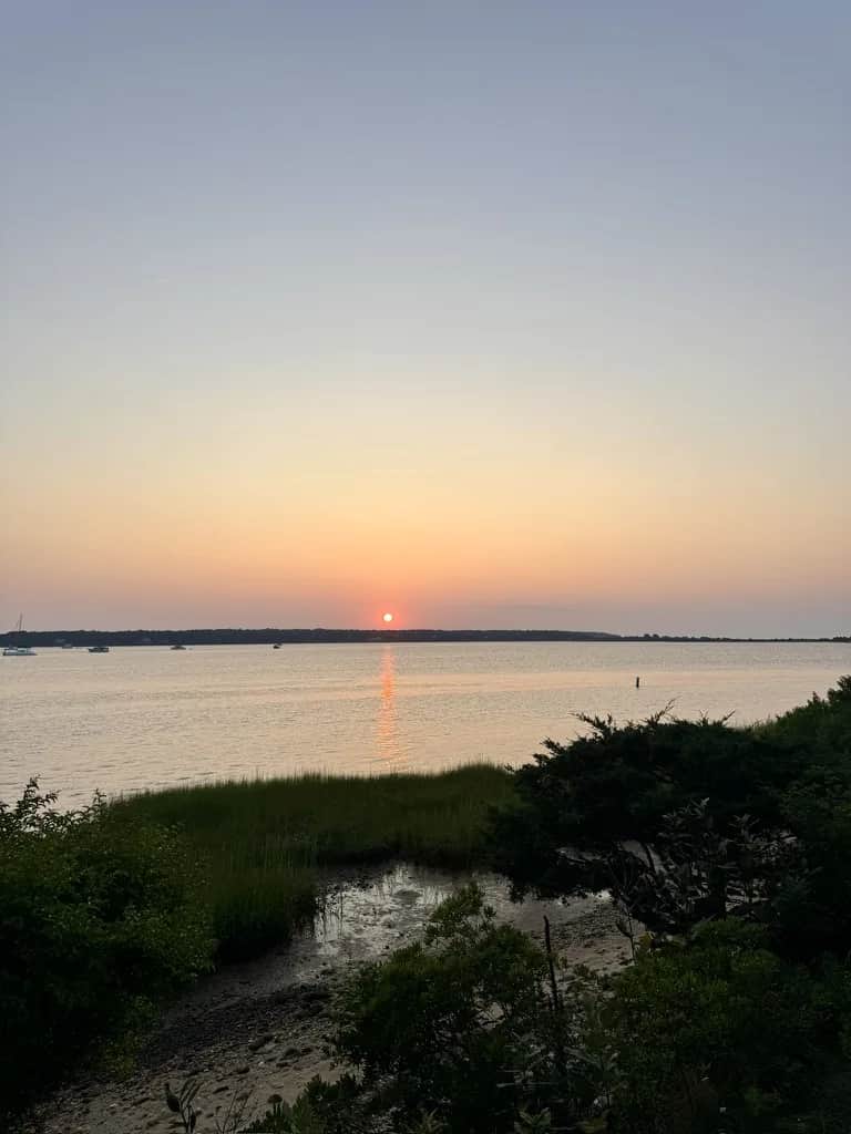 The sun going down over a tidal bay with marsh grass in the foreground