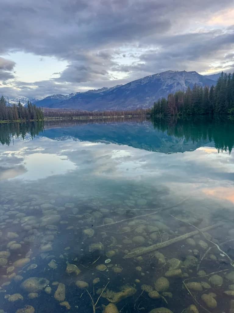 Mountains mirrored in still shallows over rounded stones, Jasper