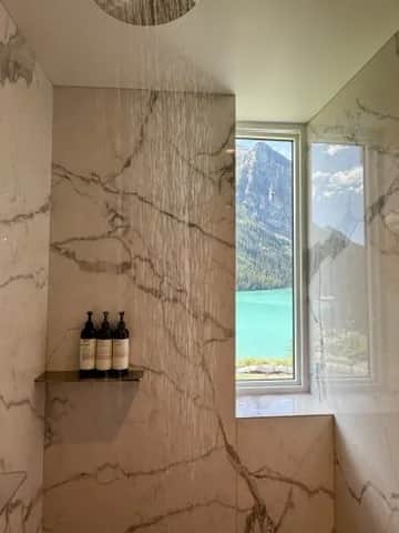 A marble shower with a window onto the lake and the mountains behind it, Lake Louise